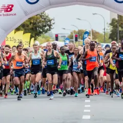 Start maratonu dla amatora. Zawodnicy pod łukiem startowym, tłum kibiców i kamerzystów.