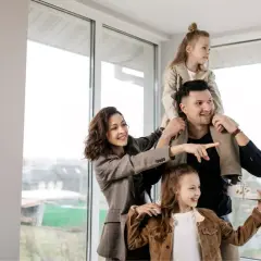 Famiglia felice in una casa luminosa, con la madre che indica il futuro. Nonostante si possa vendere casa senza lasciare a mio figlio nulla, l'amore è il vero patrimonio.