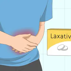 Persona con dolor abdominal, sujetándose el estómago. A su lado, una caja de laxantes, sugiriendo cómo expulsar los gases y aliviar el malestar.