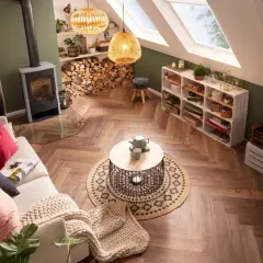 Gemütliches Wohnzimmer im Boho-Stil mit Kamin, bequemer Couch, Rattan-Lampen und vielen Pflanzen.