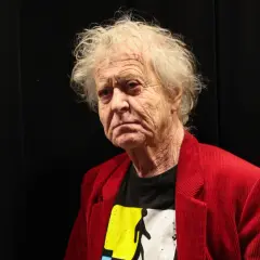 Portret Radosława Piwowarskiego, reżysera znanych filmów, w czerwonej marynarce i koszulce z grafiką.