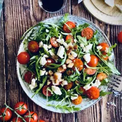 Frischer Rucola Salat mit Kirschtomaten und Feta, garniert mit Croutons. Ein leichter Genuss für warme Tage.