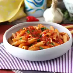 Penne all'arrabiata co to? Pikantny sos pomidorowy z czosnkiem i papryczką chili na makaronie penne, posypane natką pietruszki.