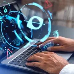 Ochrona danych wrażliwych: laptop z ikonami blokady, oka i ostrzeżeń. Ręce wpisują hasło, symbolizując bezpieczeństwo cyfrowe.