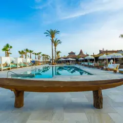 Un lujoso beach club en Mojácar con piscina, palmeras y cabañas blancas.