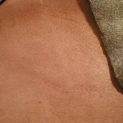 Texture d'un cuir d'agneau plongé, d'une teinte rosée, contrastant avec un cuir plus sombre et rugueux.