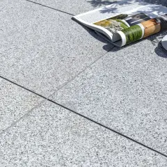 Una tazza di caffè e una rivista appoggiate su una composizione granito. La luce del sole crea ombre suggestive.