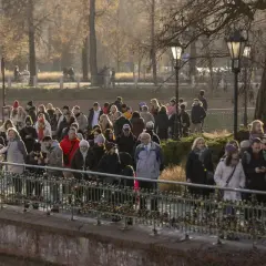 Tłum ludzi spaceruje po moście, ciesząc się słońcem. Może to ich pierwszy spacer od kiedy mają 35 dni urlopu.