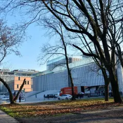 Nowoczesny budynek Centrum Spotkania Kultur na placu teatralnym w Lublinie, otoczony drzewami.