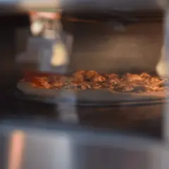 Pizza Dr. Oetker piecze się w piekarniku, apetycznie rumieniąc.