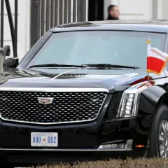 Czarne auto prezydenta USA, Cadillac Escalade, z flagami USA i Polski.