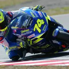 Daijiro Kato inclinado en su moto azul y amarilla, número 74, en una curva cerrada.