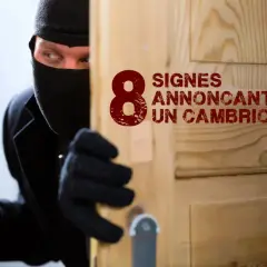Un cambrioleur masqué, vêtu de noir, jette un regard furtif par une porte entrouverte. Le texte "8 signes annonçant un cambriolage" est visible.