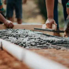 Pracownicy wyrównują świeży beton kielnią. Zastanawiasz się, ile kosztuje metr sześcienny betonu?