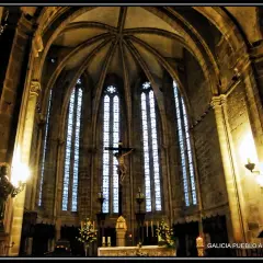 Interior de la iglesia San Francisco de Viveiro, con un crucifijo imponente y vitrales góticos.