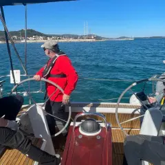 Uomini imparano a navigare durante un corso skipper, con un istruttore che guida il timone.