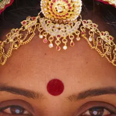 Oczy hinduski ozdobione złotą biżuterią i czerwoną bindą.