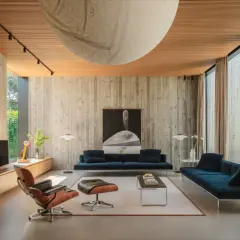 Interni in stile brutalist con pareti in cemento grezzo, soffitto in legno e mobili moderni.