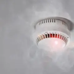 Czujka dymu piszczy, bo wykryła dym. Czerwona lampka sygnalizuje alarm.