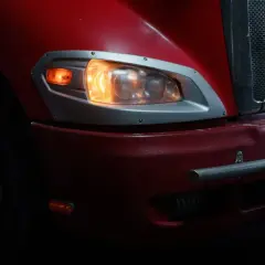 Czerwony ciągnik siodłowy z zapalonymi światłami. Zastanawiasz się, ile pali tir z naczepą?
