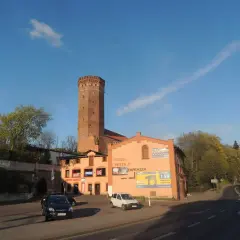 Wieża w Kamieniu Krajeńskim góruje nad budynkami z pizzerią i sklepem.