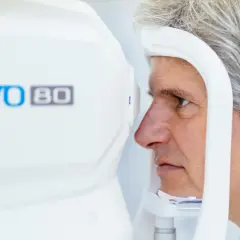 Mężczyzna poddaje się badaniu tomografia oka na nowoczesnym urządzeniu REVO 80.
