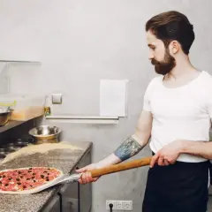 Pizzaiolo con barba prepara una pizza con farina per pizza 0 o 00.