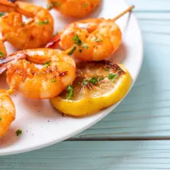 Soczyste krewetki z airfryer, podane z grillowaną cytryną i posypane natką pietruszki, kuszą apetycznym wyglądem.