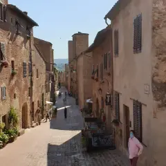 Un vicolo medievale a Certaldo, dove si trova il borgo antico con case in mattoni, finestre con persiane e fiori.