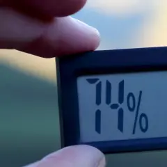 En digital hygrometer visar 74%, vilket indikerar hög luftfuktighet inomhus.