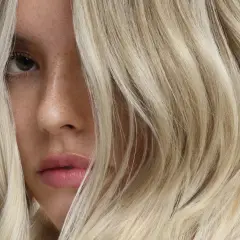 Rostro de mujer con cabello rubio platino, un ejemplo de que es matizar el pelo para un tono perfecto.