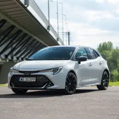 Biała Toyota Corolla GR Sport z czarnymi felgami stoi pod mostem.