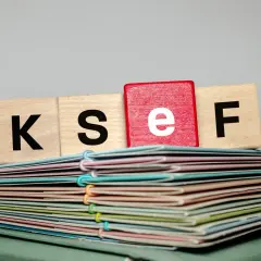 Klocki z literami K, S, E, F na stosie dokumentów. To symbol przygotowania faktury korygującej.