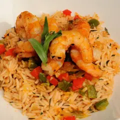 Delicioso arroz con gambas y verduras, con pimientos rojos y verdes, y una hoja verde decorativa.