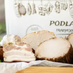 Swojskie wyroby wędliniarskie z Podlaskiej Chaty: kiełbasa, boczek, pieczone mięsa i czosnek. Tradycyjne smaki.