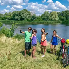 Rodzina cieszy się pięknymi trasami rowerowymi na Mazurach, pozując do zdjęcia nad jeziorem.