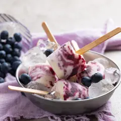 Gelato con yogurt greco e mirtilli, servito in una ciotola con ghiaccio e mirtilli freschi.