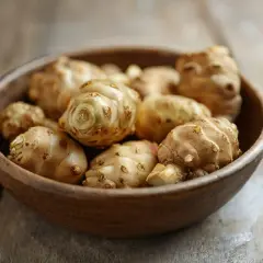 Ein Holznapf voller Topinambur-Knollen. Diese Wurzelknollen sind ein gesundes und vielseitiges Gemüse, das man kochen kann.