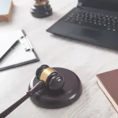 Młotek sędziowski, laptop, notatnik i książka na biurku. Czas na podjęcie decyzji celu publicznego.