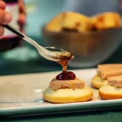 Une cuillère verse une touche de confiture sur un toast original de foie gras. Délicieux !