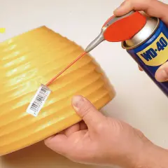 Uso di WD-40 per togliere adesivi da un oggetto giallo. Ottimo lavoro!
