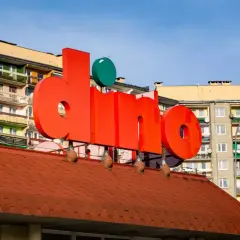 Duże czerwone litery z napisem "dino" na tle bloków mieszkalnych.