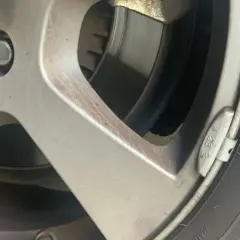 Detalle de una llanta de coche con un plomo de equilibrado de ruedas visible.