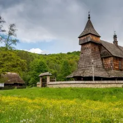 Drewniana cerkiew i chałupa na tle zielonych wzgórz. Największy skansen w Polsce zaprasza do podróży w czasie.