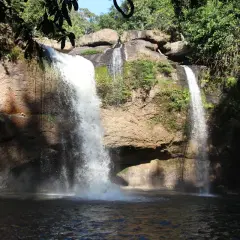 Zwei Wasserfälle stürzen in Khao Yai in einen dunklen Pool. Üppige Vegetation umgibt die Felsen.