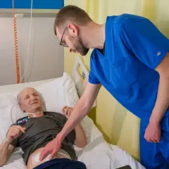 Lekarz pochyla się nad pacjentem w łóżku szpitalnym, omawiając jego rokowania po usunięciu trzustki.