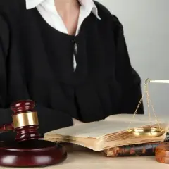 Sąd w todze, młotek sędziowski, waga sprawiedliwości i księgi prawne.