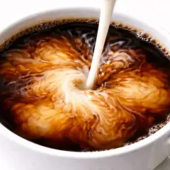 Mleko wlewane do kawy tworzy wirujące wzory. Czy cappuccino jest zdrowe? To zależy od dodatków.
