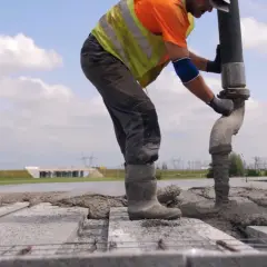 Robotnicy wylewają beton na strop Teriva. Widać pompę do betonu i zbrojenie.