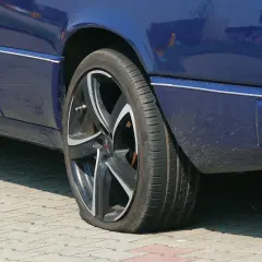 Pneu à plat sur une voiture bleue. Une situation qui pourrait compliquer un recours achat voiture particulier.
